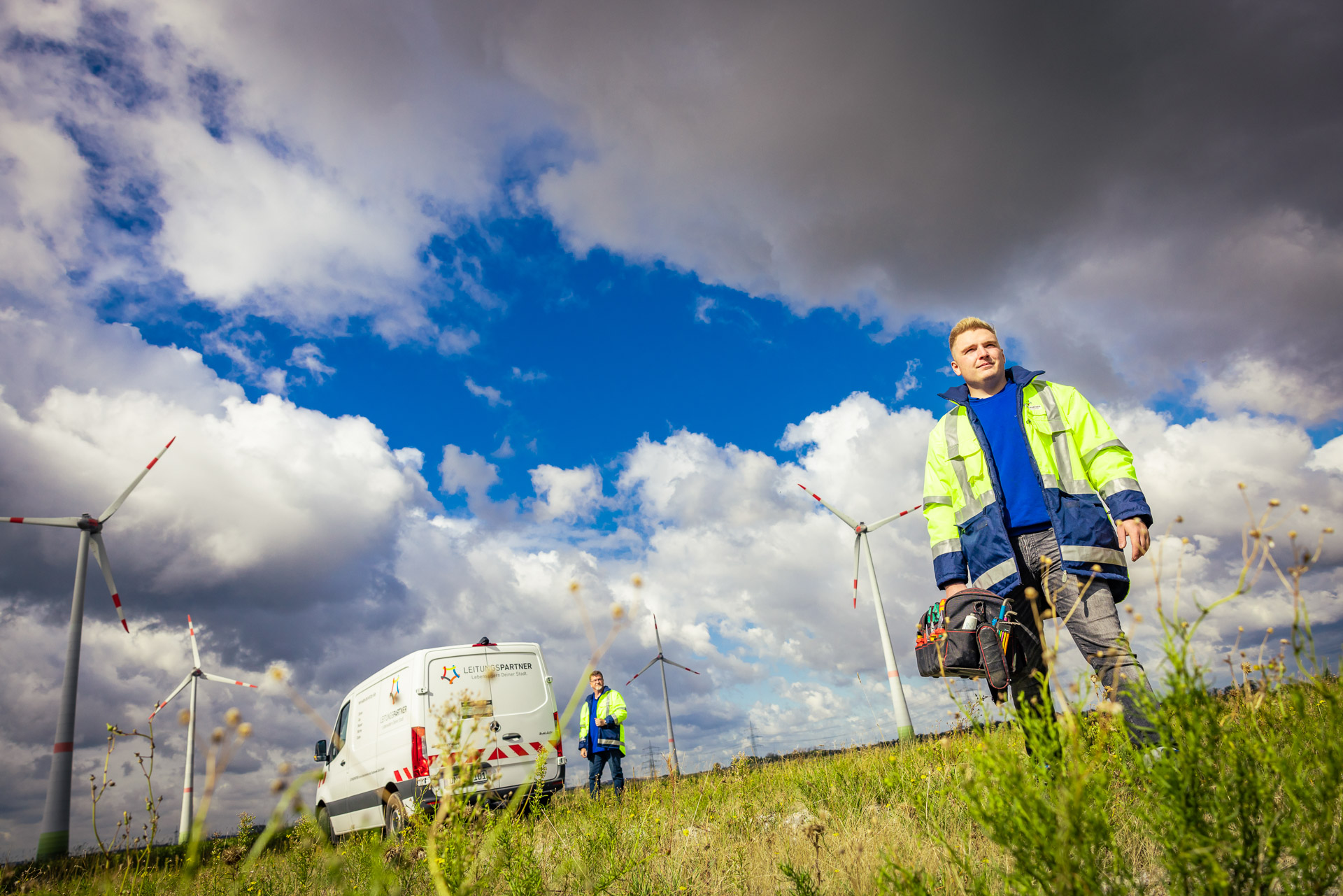 Zwei Mitarbeiter im Windpark neben einem Transporter von Leitungspartner