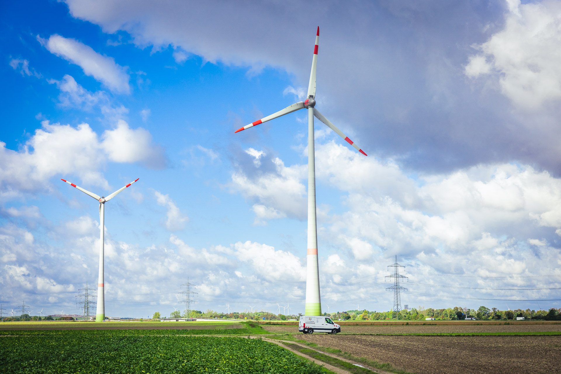 Feld mit Windrädern und dem Leitungspartner Transporter